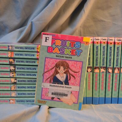 Mehrere B&auml;nde der Comic-Reihe "Fruits Basket" vor blauem Hintergrund. 