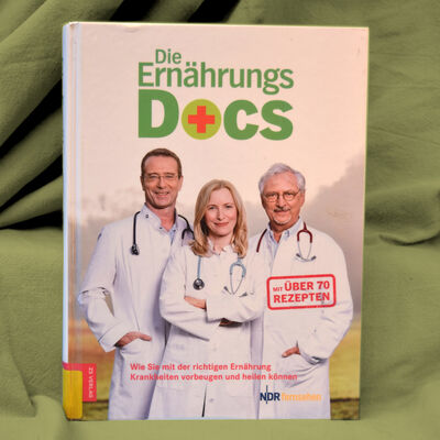 Foto des Buches "Die Ern&auml;hrungsdocs". Das Cover zeigt die drei Autorinnen und Autoren in Arztkitteln und mit um den Hals geh&auml;ngten Stethoskopen.