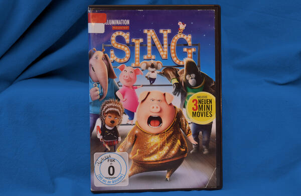 Foto der DVD "Sing". Das Cover zeigt mehrere Tiere, im Zentrum ein singendes Schwein im Glitzeranzug.