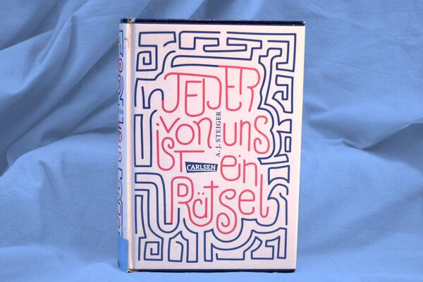 Foto des Buches "Jeder von uns ist ein R&auml;tsel". Das grafische Cover zeigt den Buchtitel als Teil eines verschlungenen Labyrinths.