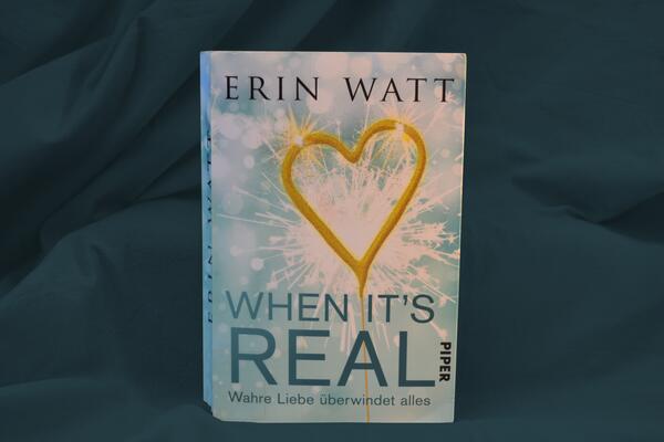 Foto des Buches "When it's real". Das Buchcover zeigt eine funkenspr&uuml;hende Wunderkerze in Herzform.