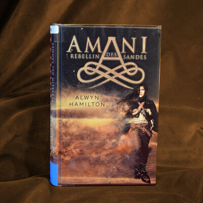 Foto des Buches "Amani - Rebellin des Sandes". Das Cover zeigt ein M&auml;dchen in western-artiger Kleidung mit Pistolengurten vor einem W&uuml;stenhintergrund.