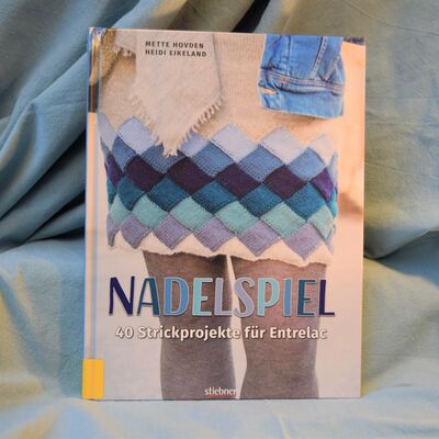 Foto des Buches "Nadelspiel". Das Cover zeigt als Beispiel einen gestrickten Rock.