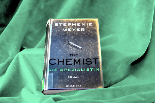 Buchfoto; das silbrige Metallic-Cover zeigt eine Spritze und darunter den Buchtitel "The Chemist - Die Spezialistin".