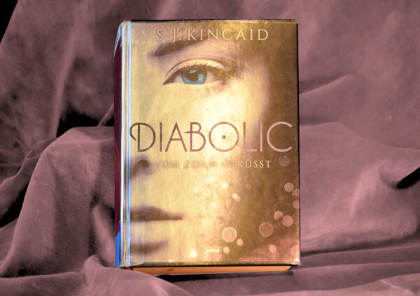 Foto des Buches "Diabolic". Das silbrige Metallic-Cover zeigt die rechte H&auml;lfte eines M&auml;dchengesichts.