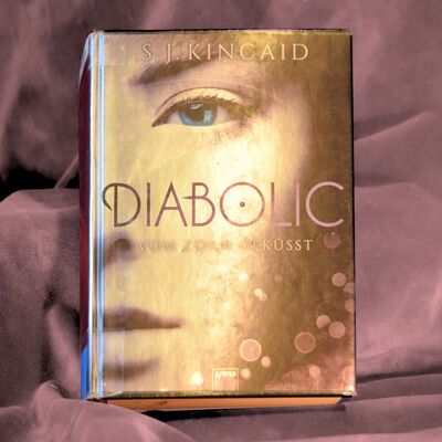 Foto des Buches "Diabolic". Das silbrige Metallic-Cover zeigt die rechte H&auml;lfte eines M&auml;dchengesichts.