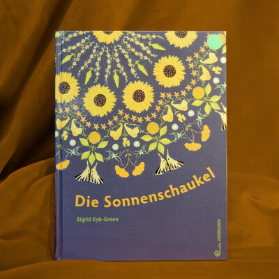 Foto des Bilderbuches "Die Sonnenschaukel". Das Cover zeigt auf dunklem Hintergrund ein kreisf&ouml;rmiges, mandala-&auml;hnliches Muster aus haupts&auml;chlich gelben und hellgr&uuml;nen Bl&uuml;ten und Bl&auml;ttern.