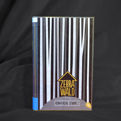 Foto des Buches "Zebrawald". Das gezeichnete Cover zeigt im Hintergrund dicht an dicht schwarze und wei&szlig;e Baumst&auml;mme, im Vordergrund umgibt ein kleines schwarzes Haus den Buchtitel.