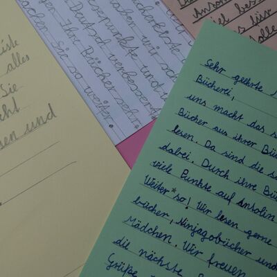 Foto von &uuml;bereinandergelegten Briefen in verschiedenen Papierfarben; es sind jeweils nur Textausschnitte des Inhalts zu lesen, keine vollst&auml;ndigen S&auml;tze.