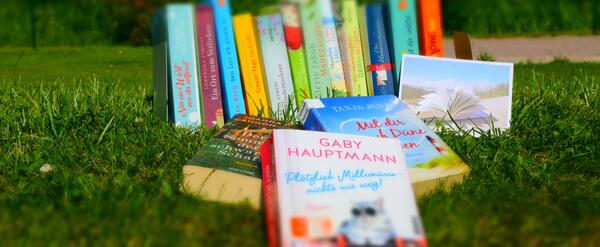 Nahaufnahme einiger Taschenb&uuml;cher drau&szlig;en im Gras, rund um Sommer und Urlaub.