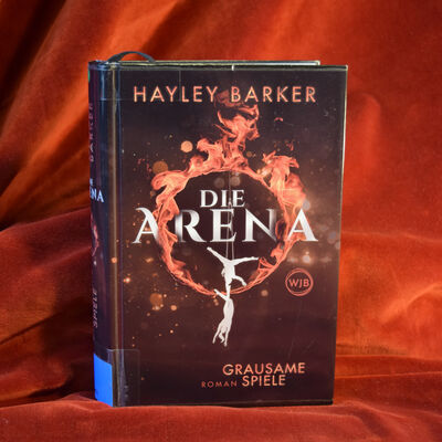 Foto des Buches "Die Arena - Grausame Spiele". Das Cover zeigt einen Feuerring, in dem die wei&szlig;en Silhouetten zweier Artisten turnen.