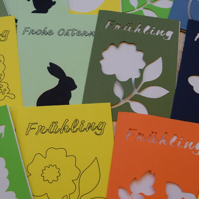 Foto mehrerer Klappkarten in verschiedenen Farben mit unterschiedlichen Motiven - zum Beispiel Blumen, Hasen, Schmetterlinge - und den Aufschriften "Fr&uuml;hling" oder "Frohe Ostern".